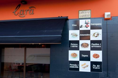 un restaurant proposant un menu sur le côté d'un bâtiment dans l'établissement Hostal Lara, à Llançà