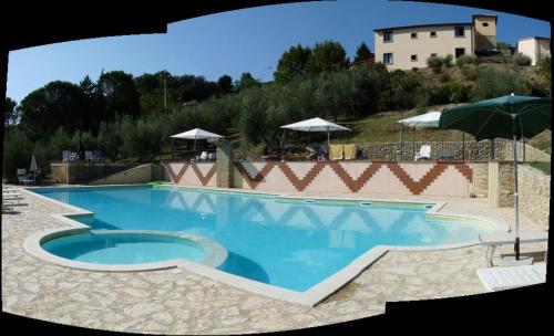 duży niebieski basen z domem w tle w obiekcie Residence Il Monastero w mieście Pomarance