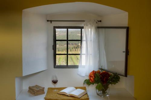 een tafel met een vaas met bloemen en een raam bij Castello Di Gabbiano in Mercatale Val Di Pesa