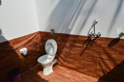 a bathroom with a toilet and a wooden floor at Soulmate Beach Resort in Agonda