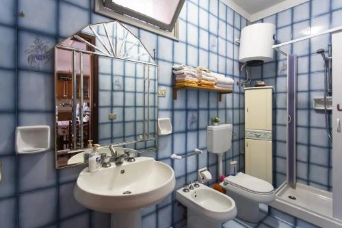 un bagno piastrellato blu con lavandino e WC di Villetta dei Tramonti a Trappeto