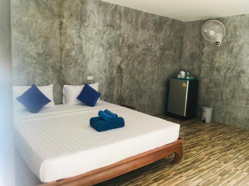 a bedroom with a bed with two blue pillows on it at Koh Yao Candy House in Ko Yao Yai