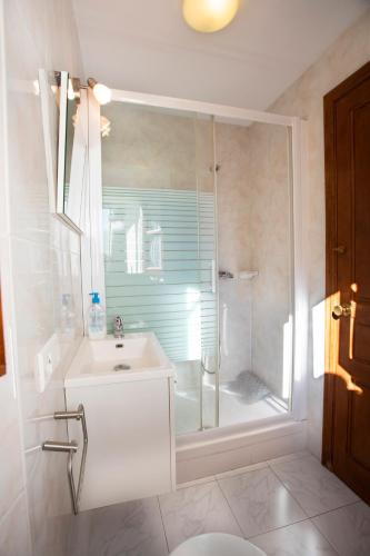 a white bathroom with a shower and a sink at Casa Güela Megustarural in Llanes