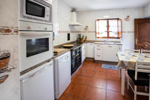 een keuken met witte apparatuur en een tafel bij Casa Güela Megustarural in Llanes