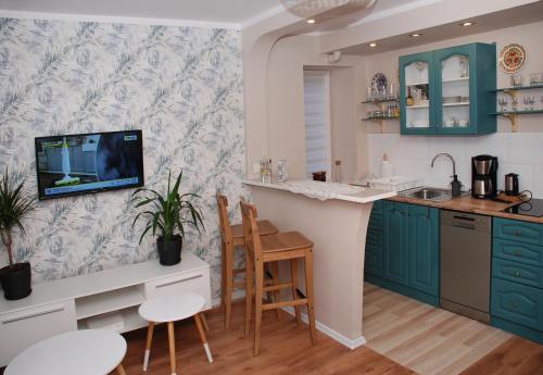 uma cozinha com armários azuis e uma televisão na parede em Apartament - Aloha 37m2 na parterze em Bytom