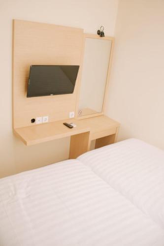 a bedroom with two beds and a tv on a desk at Merlin Hotel in Maumere