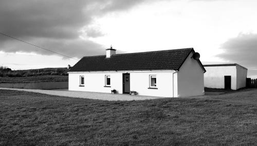 una casa blanca con un perro sentado frente a ella en Granny Dens, en Donegal