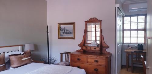 a bedroom with a bed and a dresser with a mirror at Haggards on Hilldrop in Newcastle