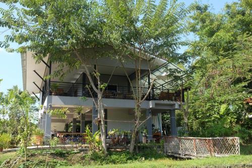 a house with a balcony and trees at Rai Boonsom in Phrao