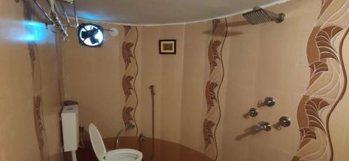 a bathroom with a toilet and a shower with curtains at The Castle View Homestay in Būndi