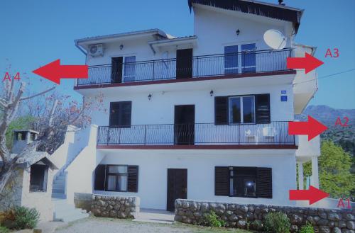 a white house with red arrows pointing to its sides at Apartments Vrša in Seline