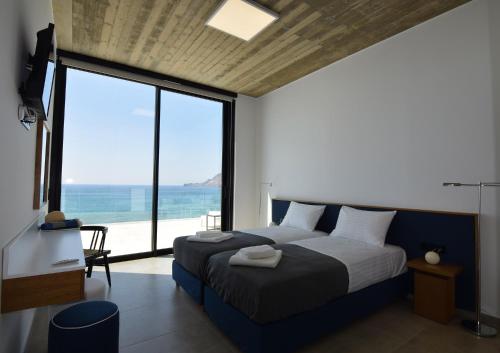 Villa Nostos Plakias beachfront sea view privet pool في بلاكاس: غرفة نوم مع سرير وإطلالة على المحيط