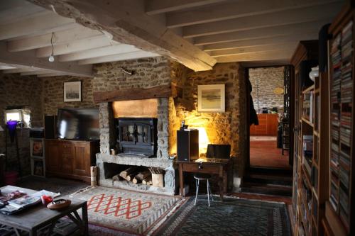 - un salon avec une cheminée en pierre et un bureau dans l'établissement La Grange Ô Belles, à Champfrémont