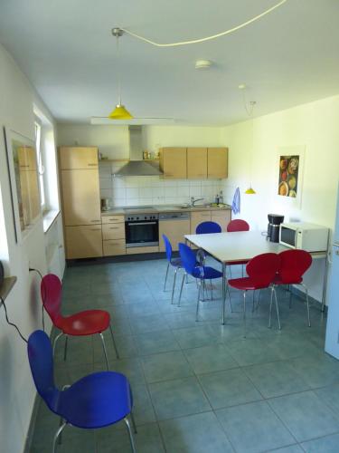 a kitchen with a table and red and blue chairs at Doppelzimmer mit Albblick in Tübingen