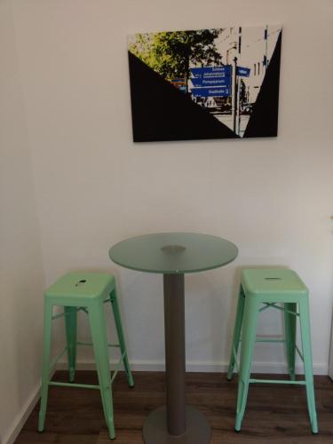 a table and two stools in front of a wall at Strietpartment - 2 Schlafzimmer, viel Raum und Ruhe in Aschaffenburg