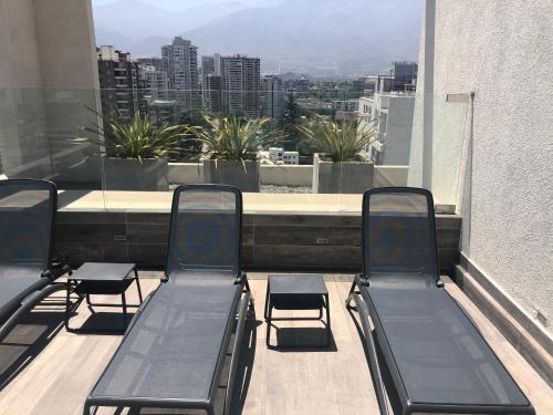 3 sillas en un balcón con vistas a la ciudad en Departamento Nuevo Plaza Ñuñoa, en Santiago