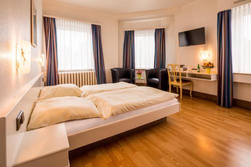 ein Hotelzimmer mit einem Bett und einem Schreibtisch in der Unterkunft Hotel Buschhausen in Aachen