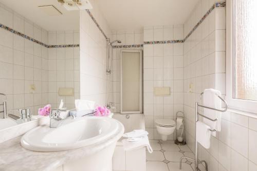 a white bathroom with a sink and a toilet at Hotel Buschhausen in Aachen