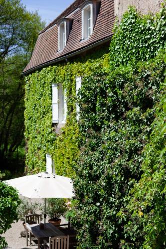 a green building with an umbrella next to a table at Moulin Renaudiots - Maison d'hôtes in Autun