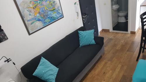 a black couch with blue pillows in a living room at Apartments Elda in Makarska