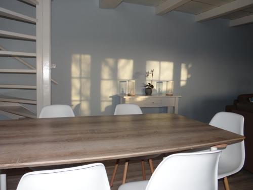 a dining room with a wooden table and white chairs at strandhuis De Bakkeete A in Kamperland
