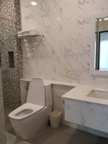 a white bathroom with a toilet and a sink at Chaisuk Bungalow in Aranyaprathet