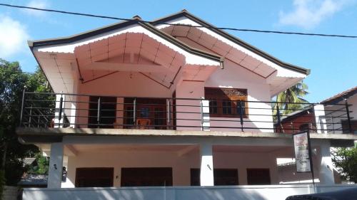 una casa rosa con balcón en la parte superior en Paradise Beach House, en Talalla South
