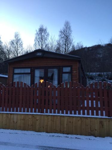 a wooden fence in front of a log cabin at 81 The Heathers, Aviemore Holiday Park , Dalfaber rd Aviemore PH22 1PX in Aviemore