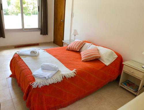 a bedroom with a large orange bed with towels on it at Titanes Pinamar in Pinamar