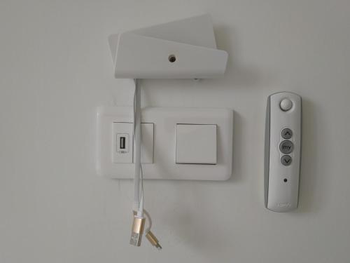 a white wall with an electrical outlet and a controller at Les Gîtes du Château de Passillé in Parigné