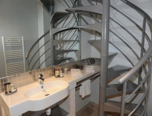 a bathroom with a sink and a spiral staircase at Le Jardin des Roches in Moigny