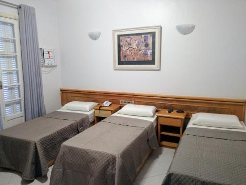 a room with four beds and a picture on the wall at Filadelfia Hotel in Sao Paulo