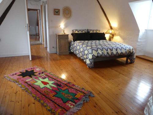 a bedroom with a bed and a rug on a wooden floor at Maison près de l'Océan in Pont-Croix