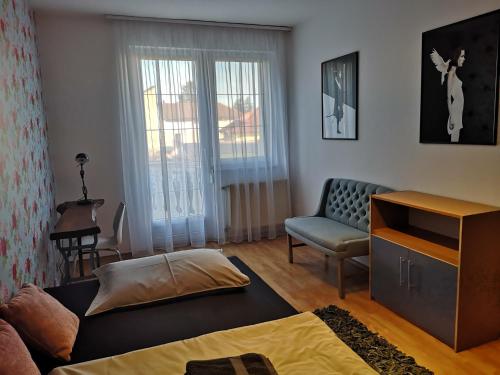 een woonkamer met een bank en een stoel bij Hotello Apartmanház és Panzió in Zalaegerszeg