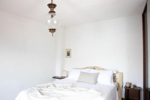a bedroom with a bed with white sheets and a chandelier at IseoLakeRental - La Stallina - Monte Isola in Monte Isola