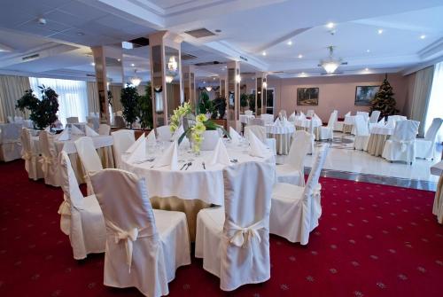 a banquet hall with white tables and chairs with white tables and chairsearcher at Hotel Ambasador Chojny in Łódź