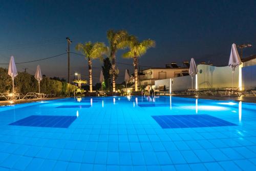 a large blue pool at night with palm trees at Sun Maris in Faliraki