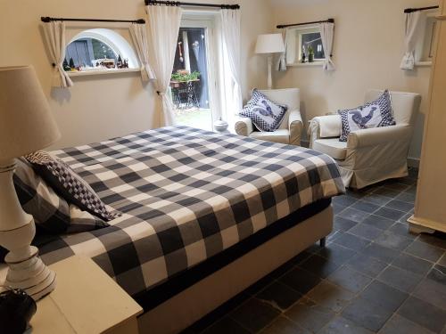 a bedroom with a bed and two chairs and a window at bij Saar in Zwinderen