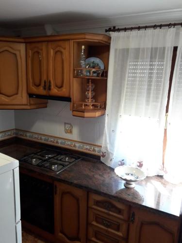 a kitchen with wooden cabinets and a stove and a window at Casa La Huerta in Bubión