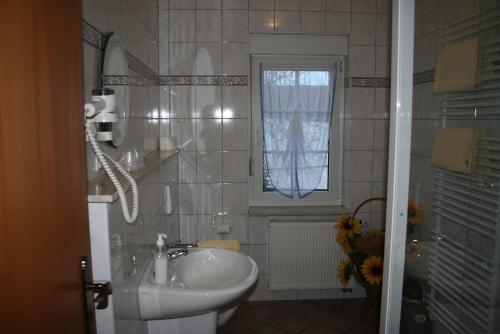 a bathroom with a sink and a toilet and a window at Pension zur Krone in Eisenach