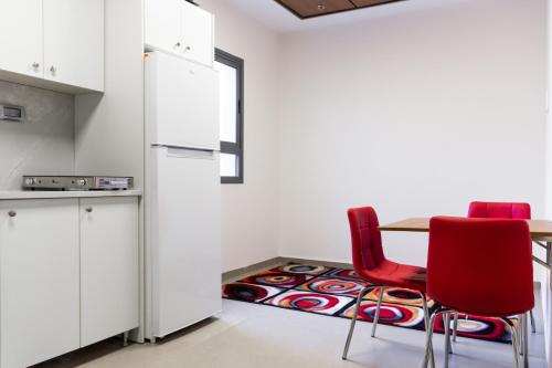 a kitchen with red chairs and a table with a rug at Amwaj Apartments in Nazareth