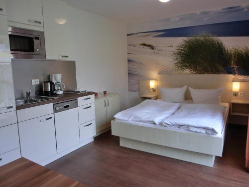 a bedroom with a white bed and a kitchen at Fewo mit Terrasse in Gelbensande