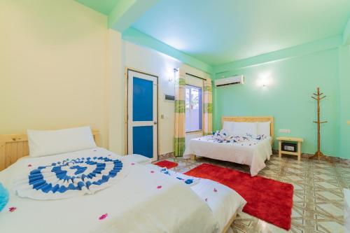 a bedroom with two beds and a red rug at Olhumathi View Inn in Ukulhas