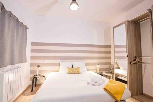 - une chambre avec un grand lit blanc et une couverture jaune dans l'établissement La cour du faubourg 3, à Strasbourg