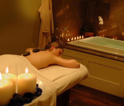 a man laying in a bath tub in a bathroom with candles at The White Barn Inn & Spa, Auberge Collection in Kennebunk