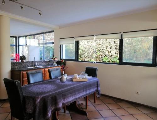 une salle à manger avec une table et quelques fenêtres dans l'établissement Surf & Guest Lorena´s House, à Ribeira Grande