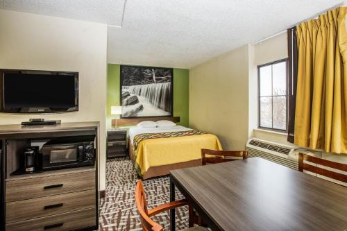 a small hotel room with a bed and a tv at Super 8 by Wyndham Wichita East in Wichita