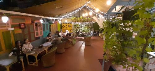 a room with people sitting at tables and plants at NAMASTEY MUMBAI BACKPACKERS in Mumbai