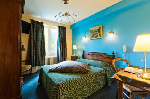 Saint-Gervais-dʼAuvergneにあるRelais d'Auvergneの青い壁のベッドルーム1室、ベッド1台、テーブルが備わります。