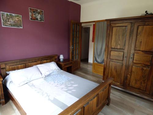 1 dormitorio con cama y pared púrpura en Gîte 3 étoiles chez Nath et Tony, en Taurinya